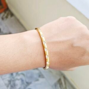 Elegant gold-tone slim kada bracelet with crystal stone accents for women.