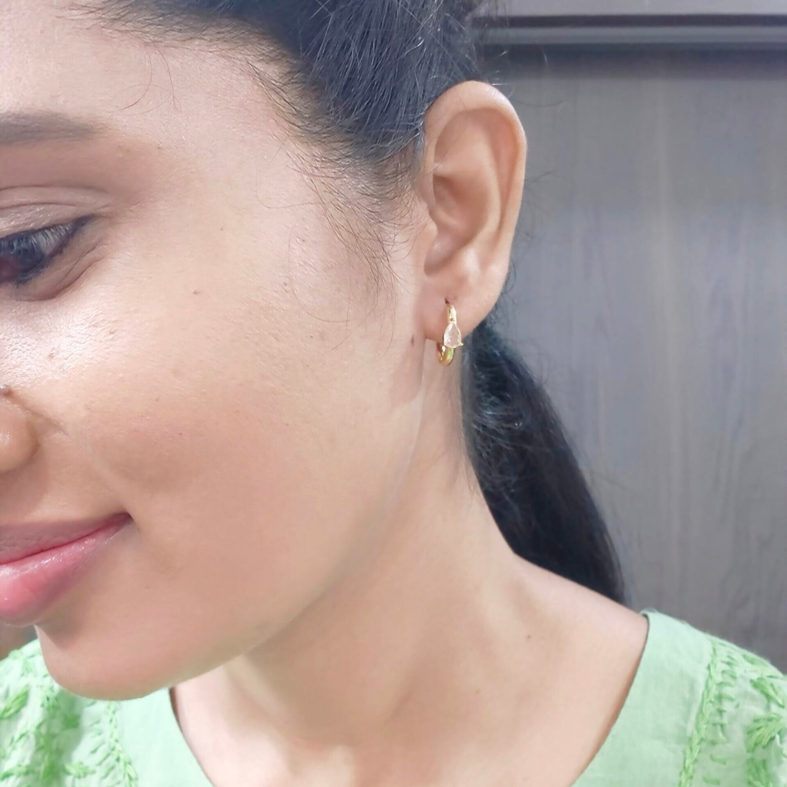 Gold huggie hoop earrings with a pear-cut crystal for women.